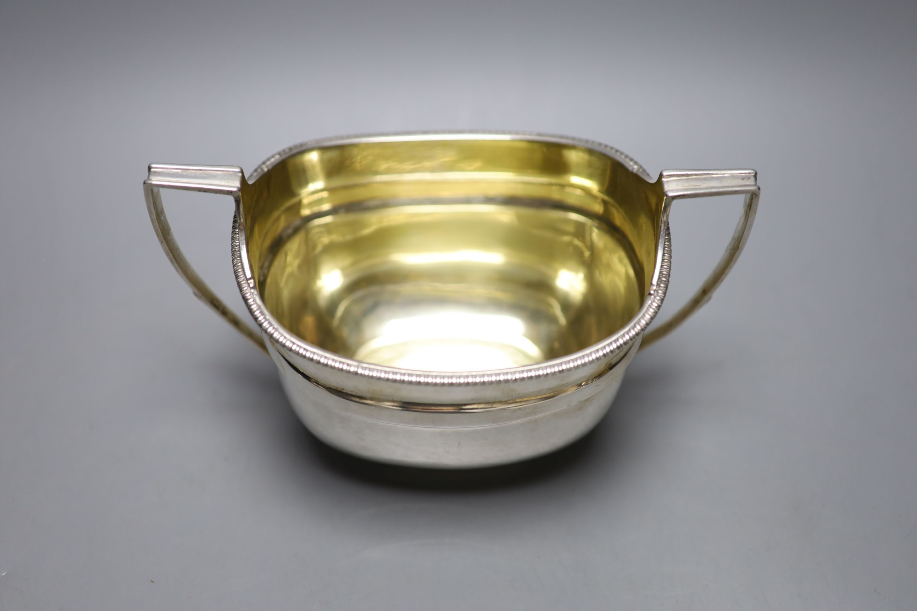 A George III silver two handled sugar bowl, John Emes, London, 1807, height 11.2cm, together with a later silver cigarette case, gross 11oz.